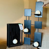 Both black metal candle holders displayed with white ball candles inserted