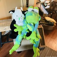 Cow plush, frog plush and small frog plush on chair
