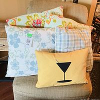 All five decorative cushions stacked on an upholstered chair