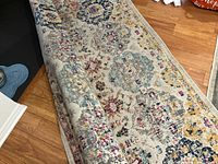 Rug partially rolled back showing colourful pattern and underside