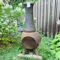 Full view of rusted metal chiminea showing front mesh door and detachable chimney