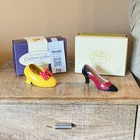 Both ceramic shoe figurines with their branded boxes on wooden surface