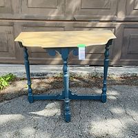 Full front view of two-tone console table showing top, legs and stretcher