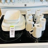 Stacked square plates, bowls and mugs on stovetop