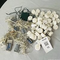 Fairy light strands with battery packs and pile of flameless tea lights displayed on table