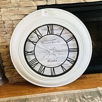 Front view of the 30" Greenwich Clock Co. round wall clock leaning against stone wall