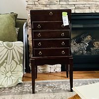 Full view of jewelry armoire on stand showing five drawers and brass pulls
