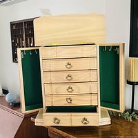 Open jewelry box showing lid, side doors, drawers, velvet lining