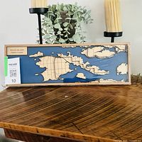 Front view of rectangular layered wooden and resin map of Wolfe Island on wooden shelf