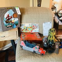 Overall lot showing mountain playset, red case, launcher with car, dinosaur figure and instruction sheet