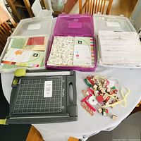 Overview of three storage cases of paper, paper trimmer, stamps and embellishments