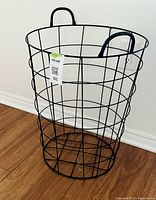 Full view of cylindrical black metal wire basket against wall