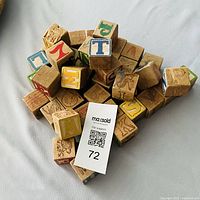 Pile of vintage wooden alphabet blocks showing letters, animal carvings, wear