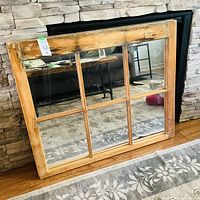 Front view of the six-pane vintage window frame mirror leaning against a stone wall