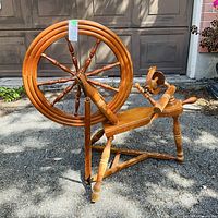 Full view of spinning wheel standing outdoors showing drive wheel, flyer, treadle and overall condition
