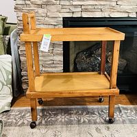 Full view of wooden two-shelf cart showing handle, shelves, legs and casters