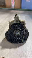 Front view of black beaded purse with brass frame and cabochon medallion