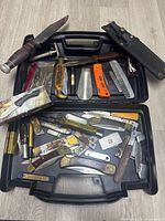 Open plastic case showing assorted knives, razors, comb, shoehorn, level