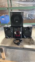 Full stereo system with two speakers, subwoofer on top, and Sony headphones in front