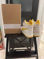 Steve Madden shoe box beside Nike high-tops on stool