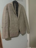 Front view of beige quilted blazer on hanger
