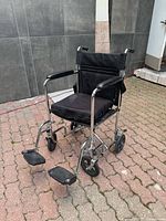 Front-side view of chrome transport wheelchair with footrests attached