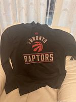 Front view of black hoodie showing Toronto Raptors logo and wordmark