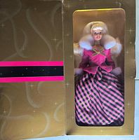 Front view of sealed box opened to show Barbie in pink outfit with plaid skirt