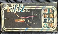 Lid of the 1977 Star Wars board game showing X-wing, TIE fighters and character portraits
