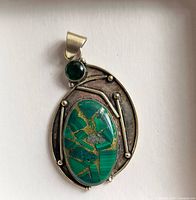 Front view of sterling silver pendant showing oval green stone with gold veining and round green cabochon