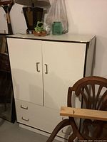 Front view of white cabinet showing two doors and two drawers, gold trim and handles visible