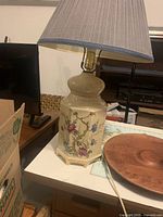 Full view of ceramic lamp base and shade showing floral design and wooden feet