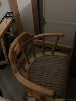 Light oak captain’s armchair with striped cushioned seat next to bicycle