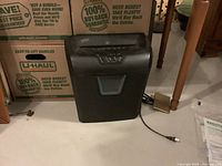 Front view of black Staples shredder showing top control panel, integrated bin, and power cord