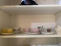 Shelf with assorted bone china teacups, saucers and sugar bowl
