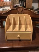 Front view of wood desktop organizer showing four upper compartments and lower drawer