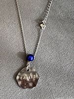 Full view of sterling silver necklace showing chain, pendant, blue bead