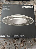Front of retail box showing Artika Essence Disk LED ceiling light with specs