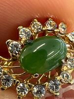 Front view showing green cabochon and surrounding clear stones