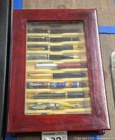 Closed wooden display case showing pens through glass top