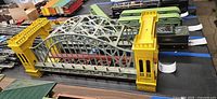 Overall view showing complete bridge with yellow towers, grey-green truss, red base