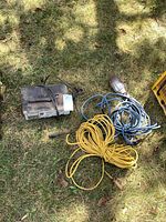 Battery charger, trouble light with cord, yellow rope on grass