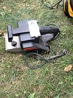 Side view of Craftsman belt sander with cord and plug visible on grass
