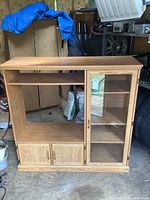 Front view showing entire entertainment stand with open bay, glass door, shelves, lower cabinet