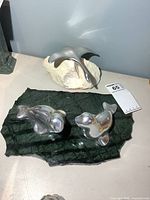 Manta ray sculpture on cream stone and seal/dolphin sculpture on green stone