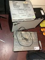 Craftsman router table extension kit box atop amplifier with table visible below