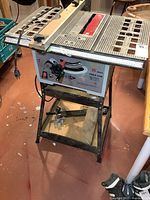 Full view of Brico table saw on stand showing controls, cord and overall wear