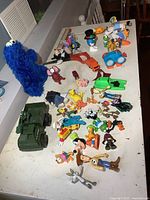 Overview showing plush Cookie Monster, numerous small character figurines and vehicles on tabletop.