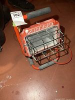 Front view of red Power Light halogen work light showing cage and housing