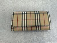 Front view of closed wallet showing beige plaid pattern and snap flap
